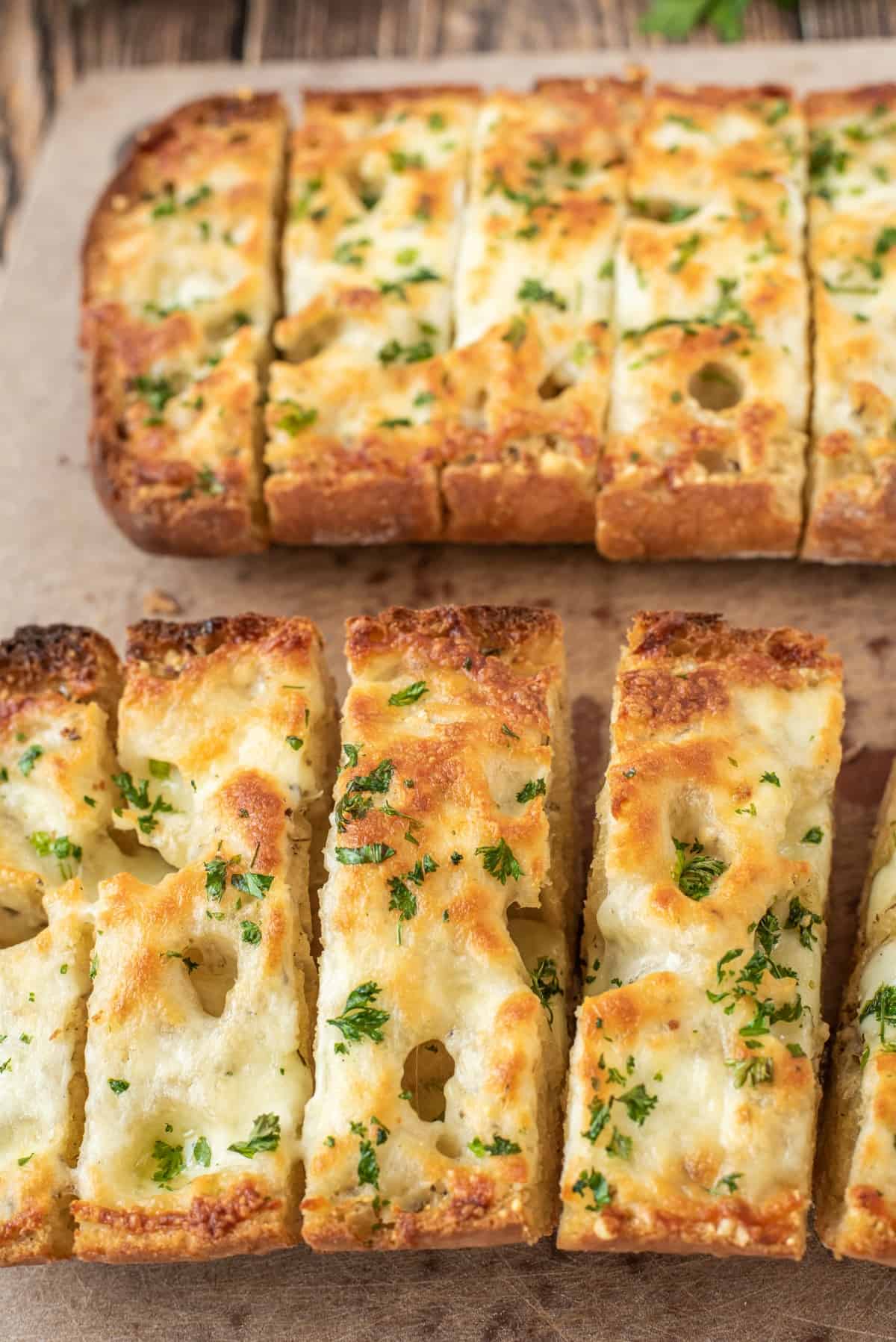 Cheesy garlic bread on parchment paper, sliced.