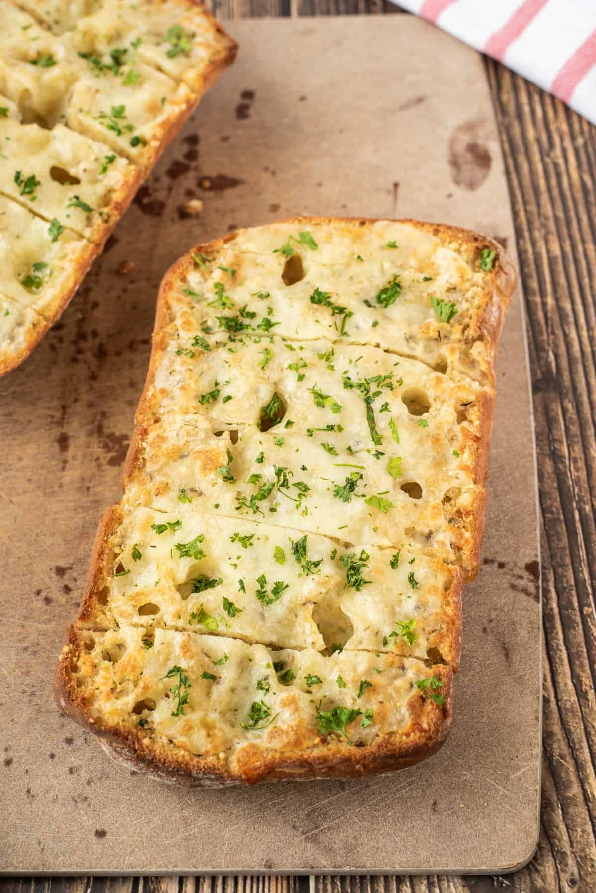 cheesy garlic bread, uncut, on baking sheet.
