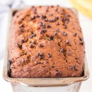 Loaf of banana bread with chocolate chips in a metal baking pan.