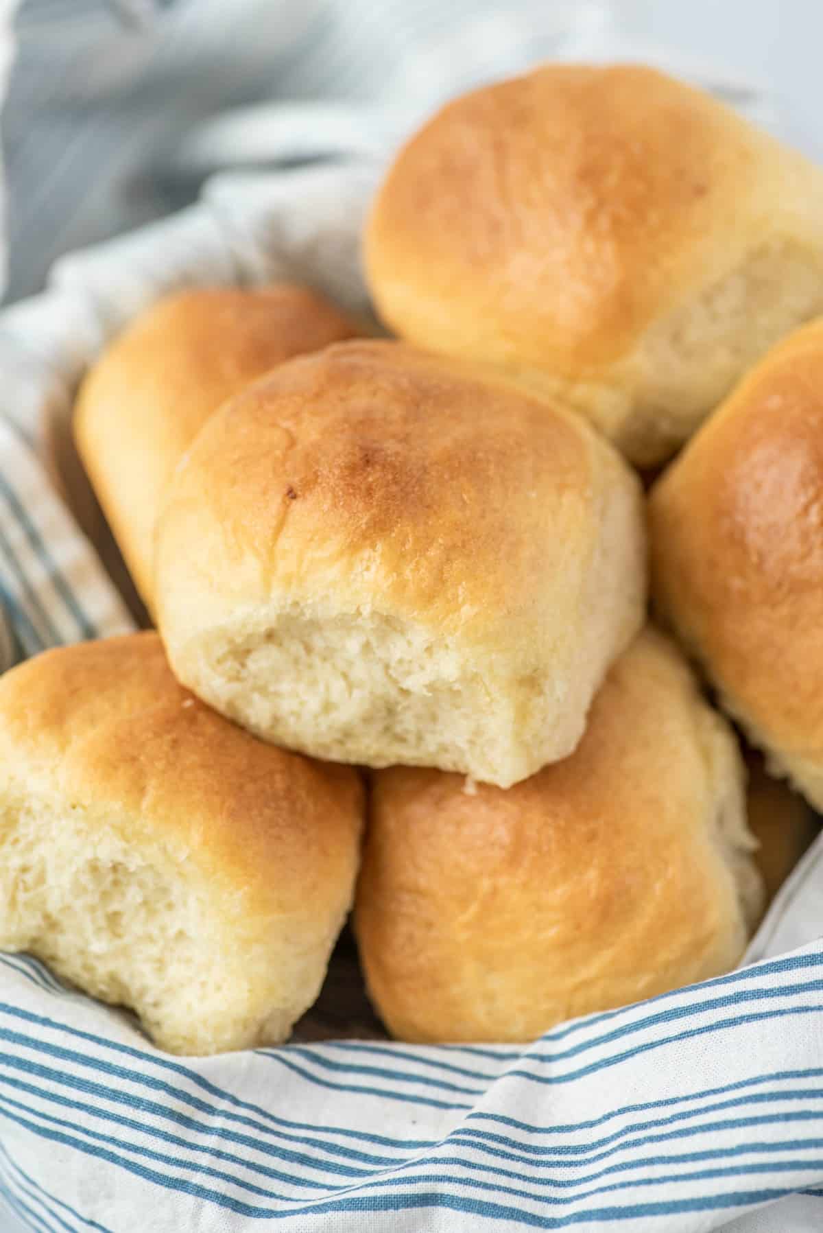 Linen lined basket filled with fluffy dinner rolls.