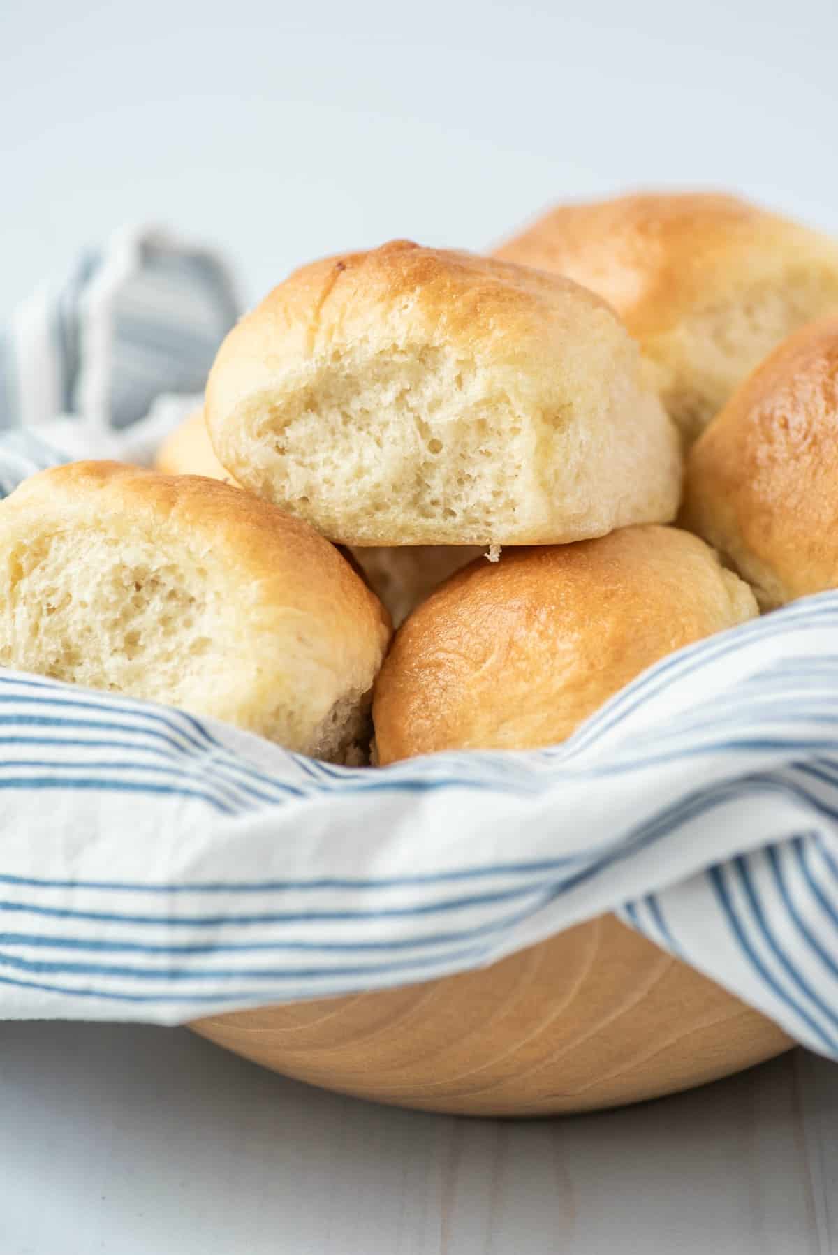 Bowl of fluffy baked dinner rolls .