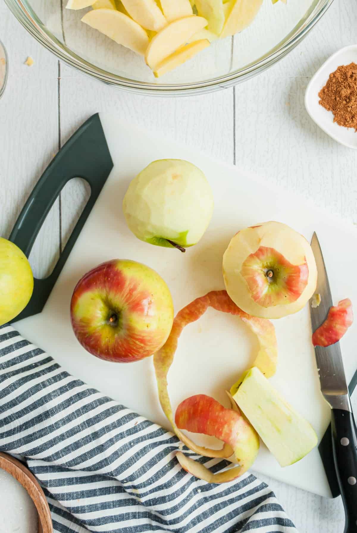 Apples on a white board being peeled.