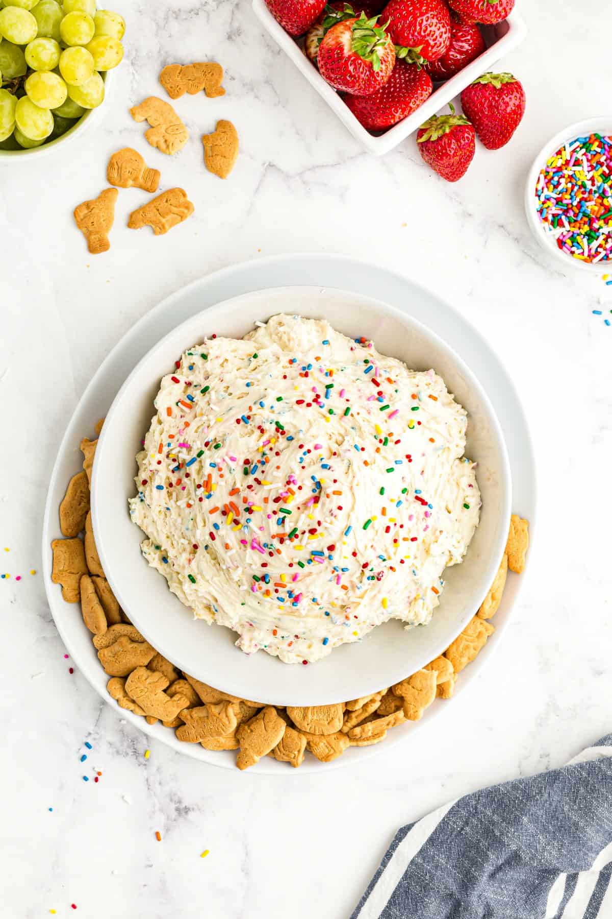 Cake batter dip in a white bowl with sprinkles and served with animal crackers.