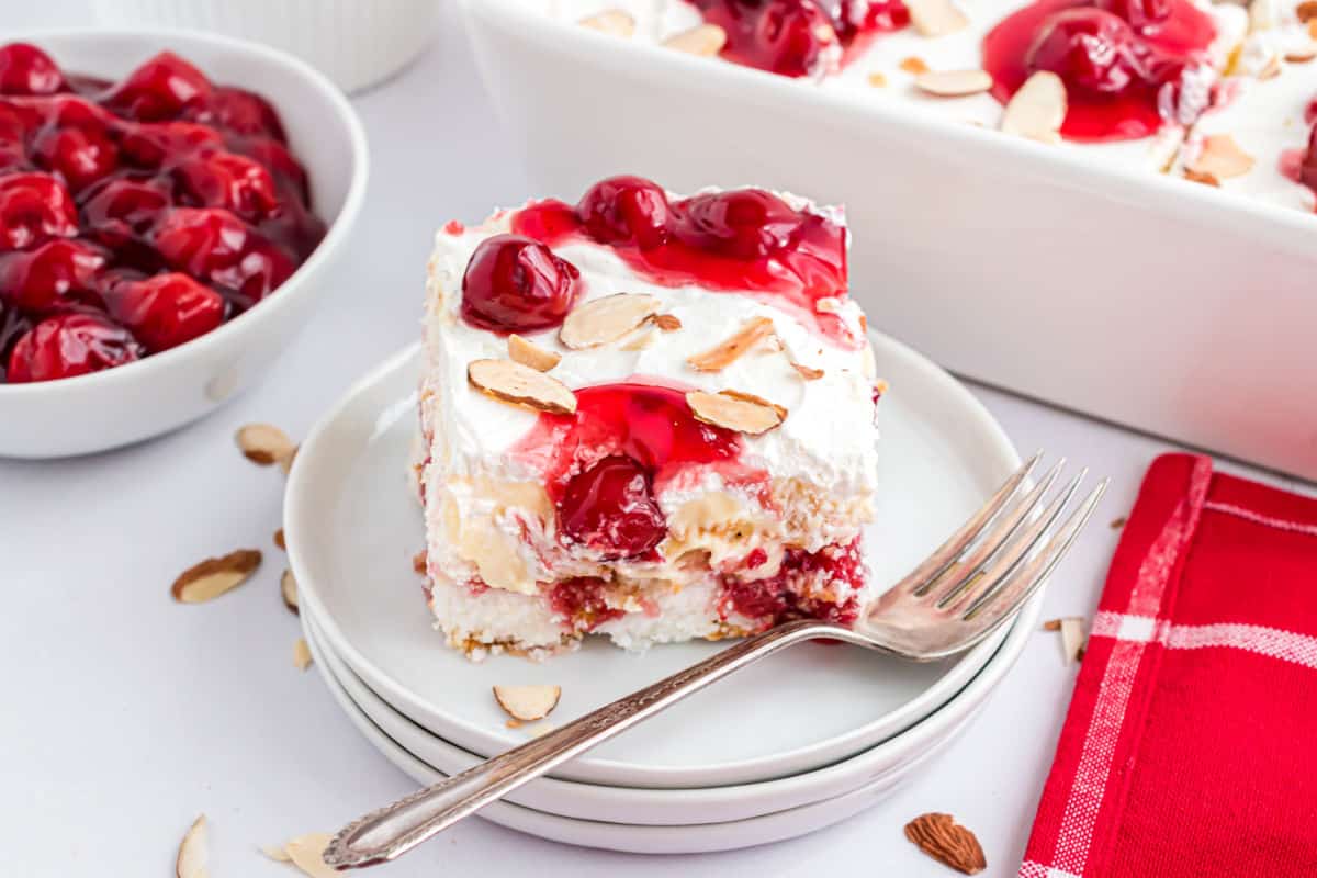 Slice of heaven on earth cake on a stack of white plates.