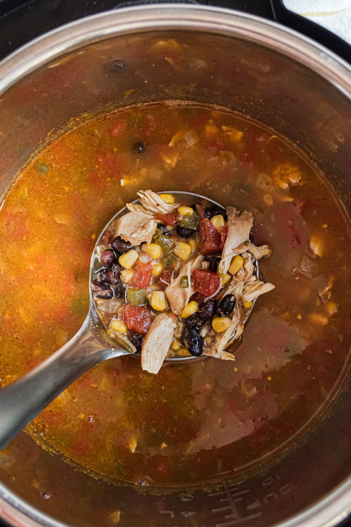 Chicken tortilla soup in instant pot being lifted out with a ladle.