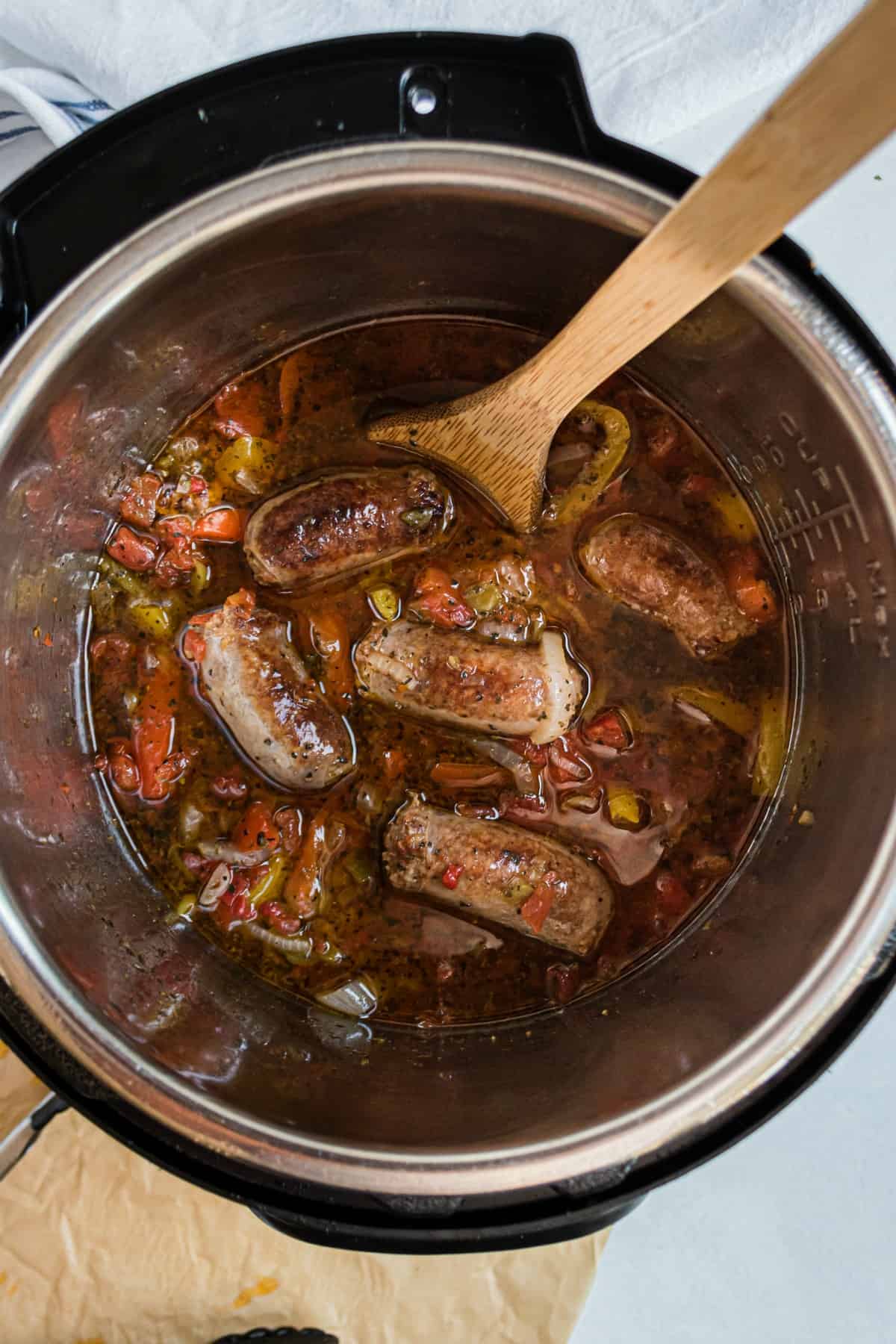 Instant Pot filled with italian sausage, peppers, and rotel tomatoes.