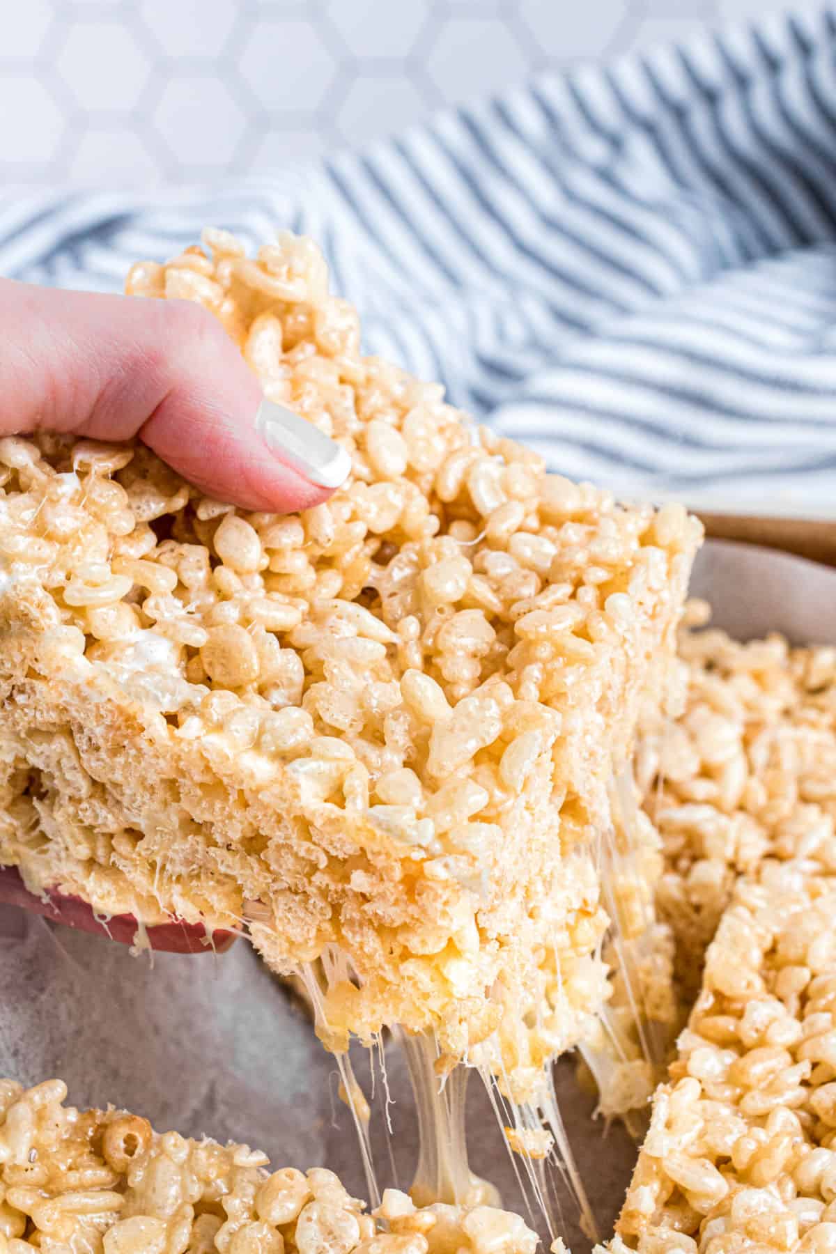 Gooey rice krispie treat being pulled out of the baking dish.
