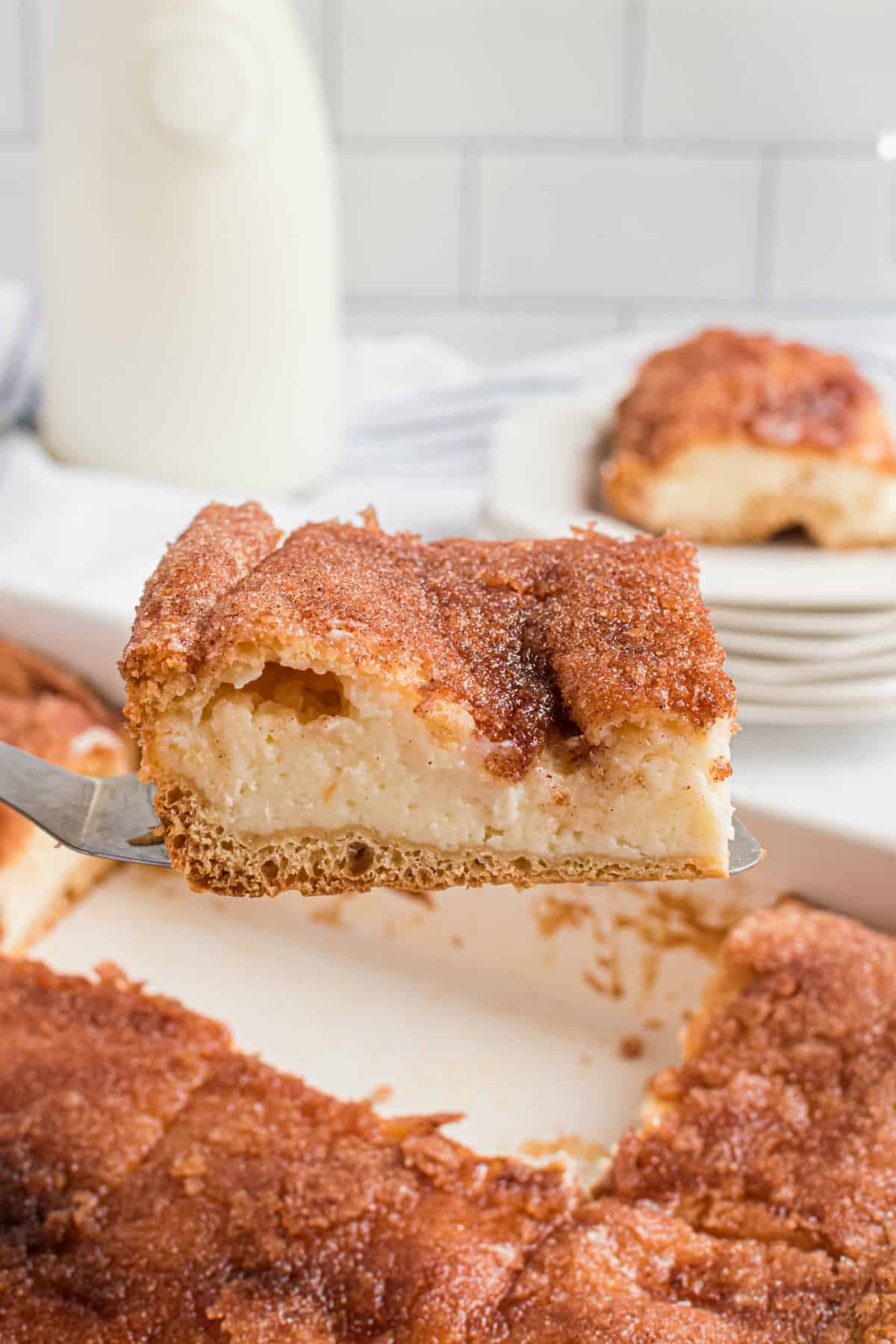 Slice of sopapilla cheesecake being lifted out of a white 13x9 dish with a spatula.