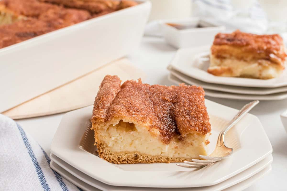 Sopapilla cheesecake bar on a white plate with a fork.