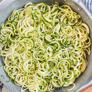 Zoodles in a skillet with salt and pepper.