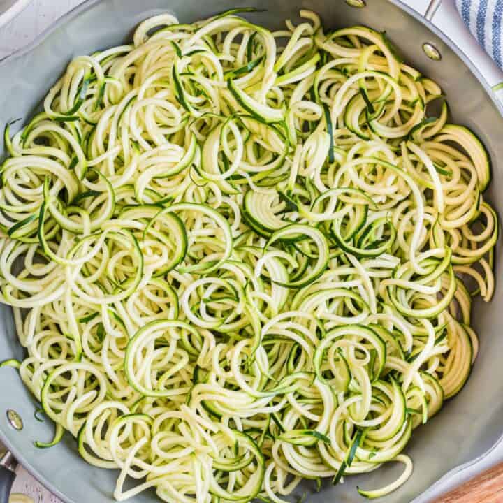 Zoodles in a skillet with salt and pepper.