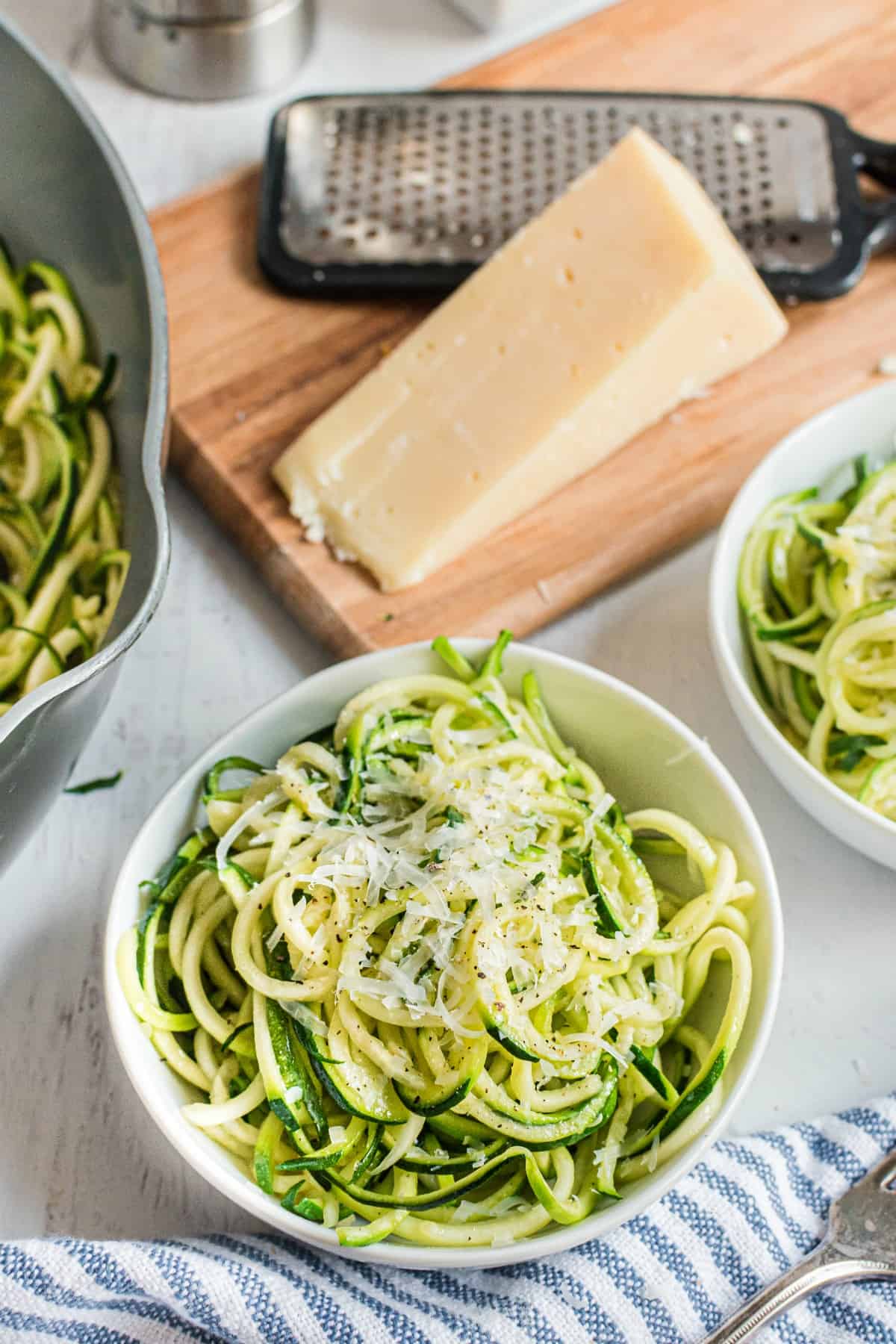 Zoodles in a bowl topped with parmesan cheese.