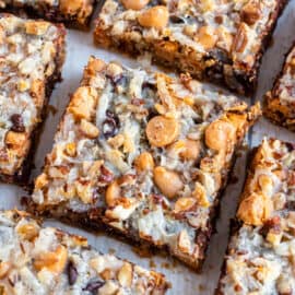 Gooey 7 layer bars on a parchment paper lined cookie sheet.