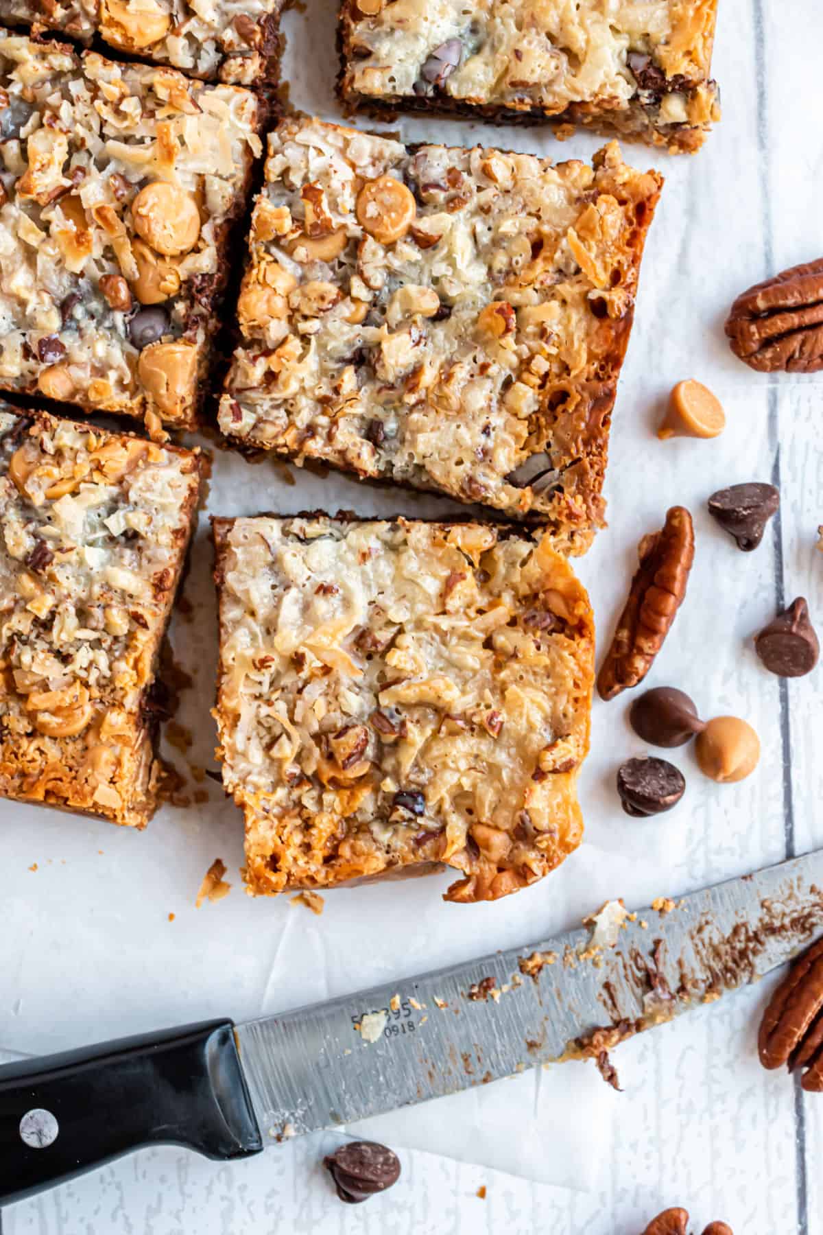 7 layer bars cut with a sharp knife on cutting board.