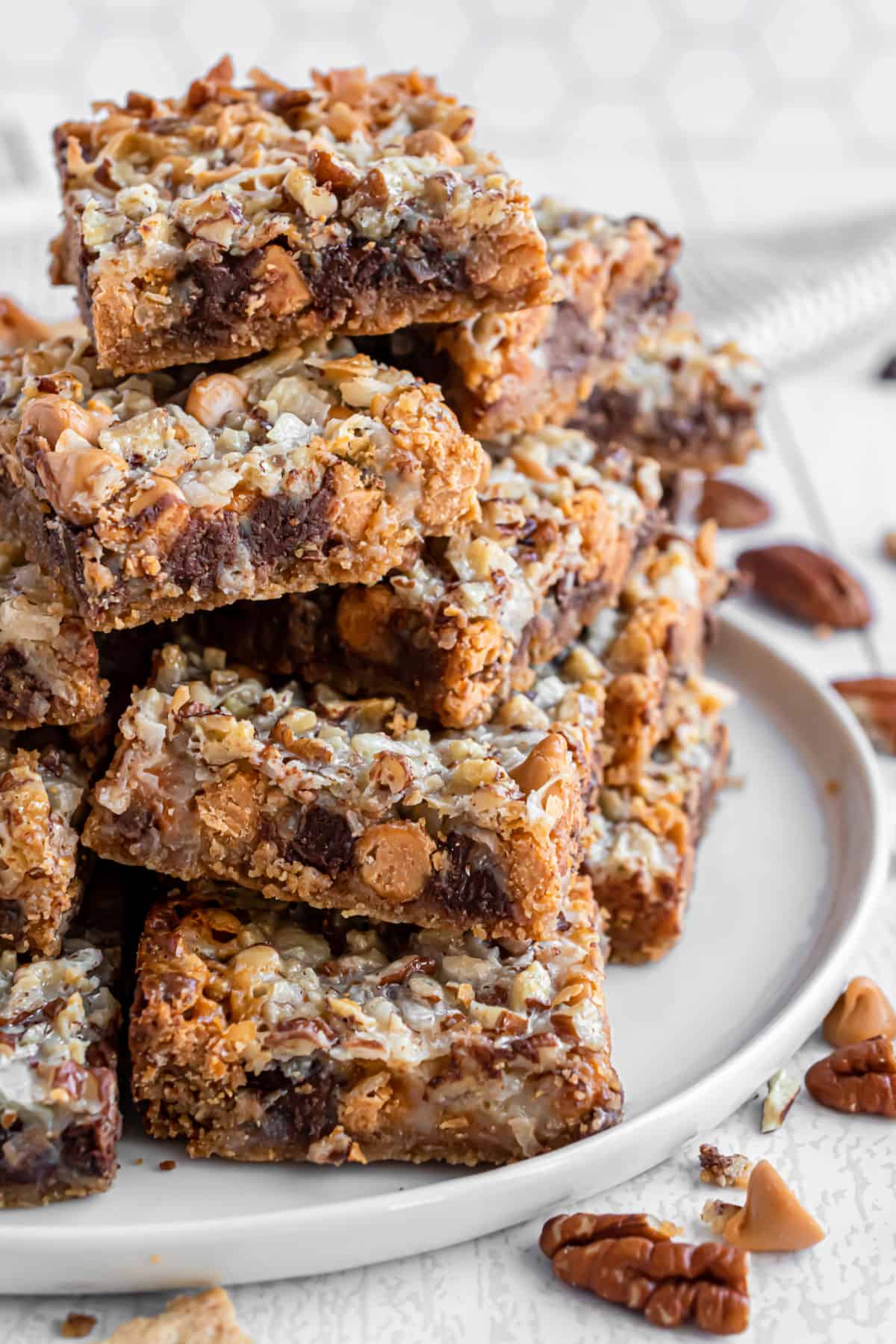 Seven layer magic bars stacked on a white plate.