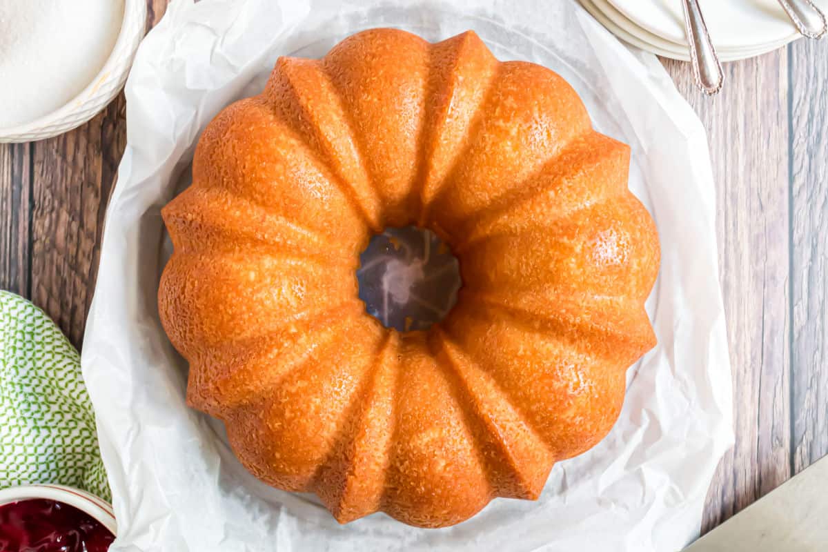 Pound cake uncut on a cake platter with parchment paper.