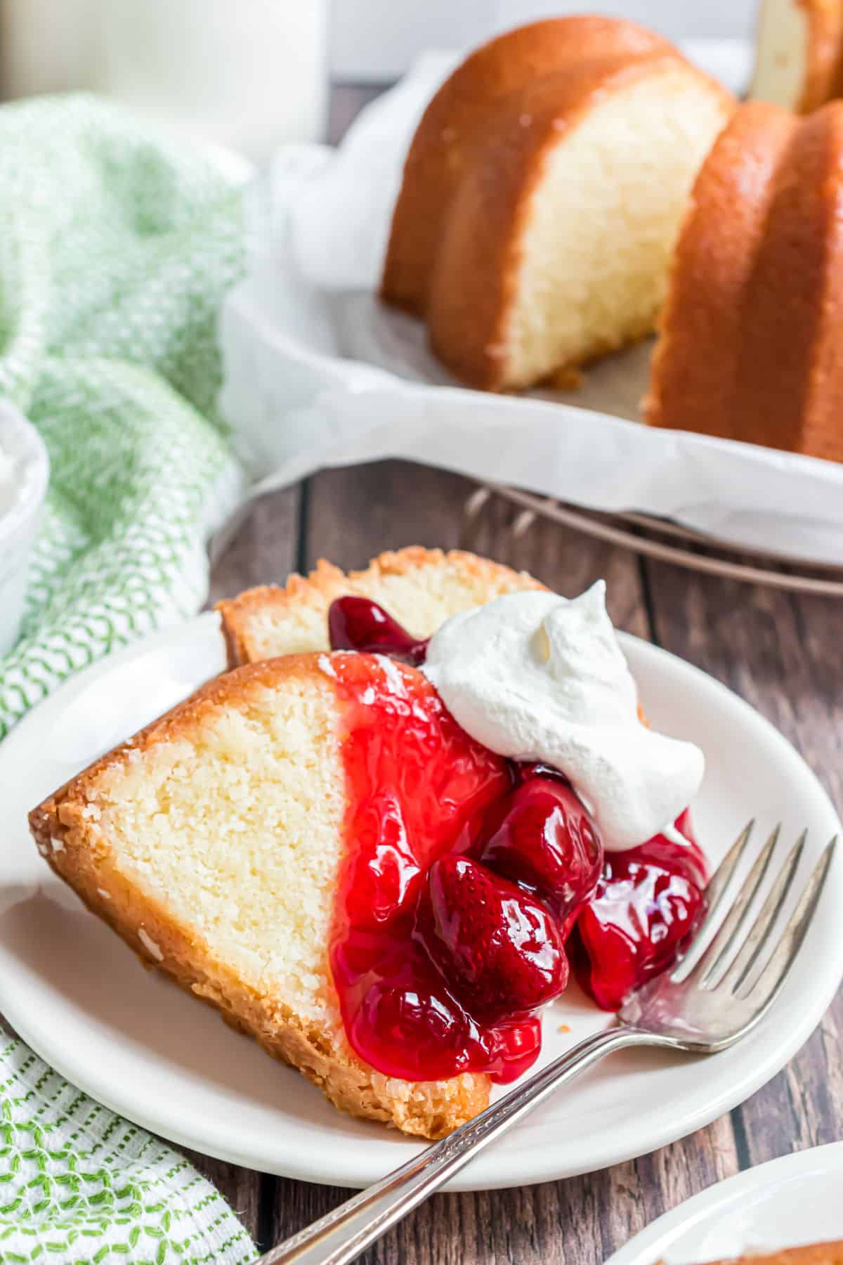 Slices of pound cake on a plate with strawberry and whipped cream.
