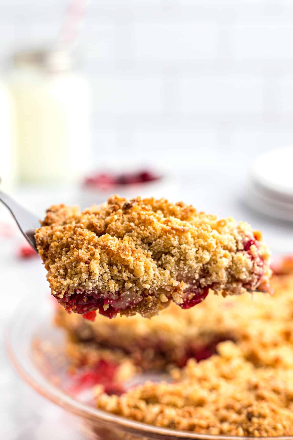 Slice of apple cranberry crumble being lifted out of the pie plate.