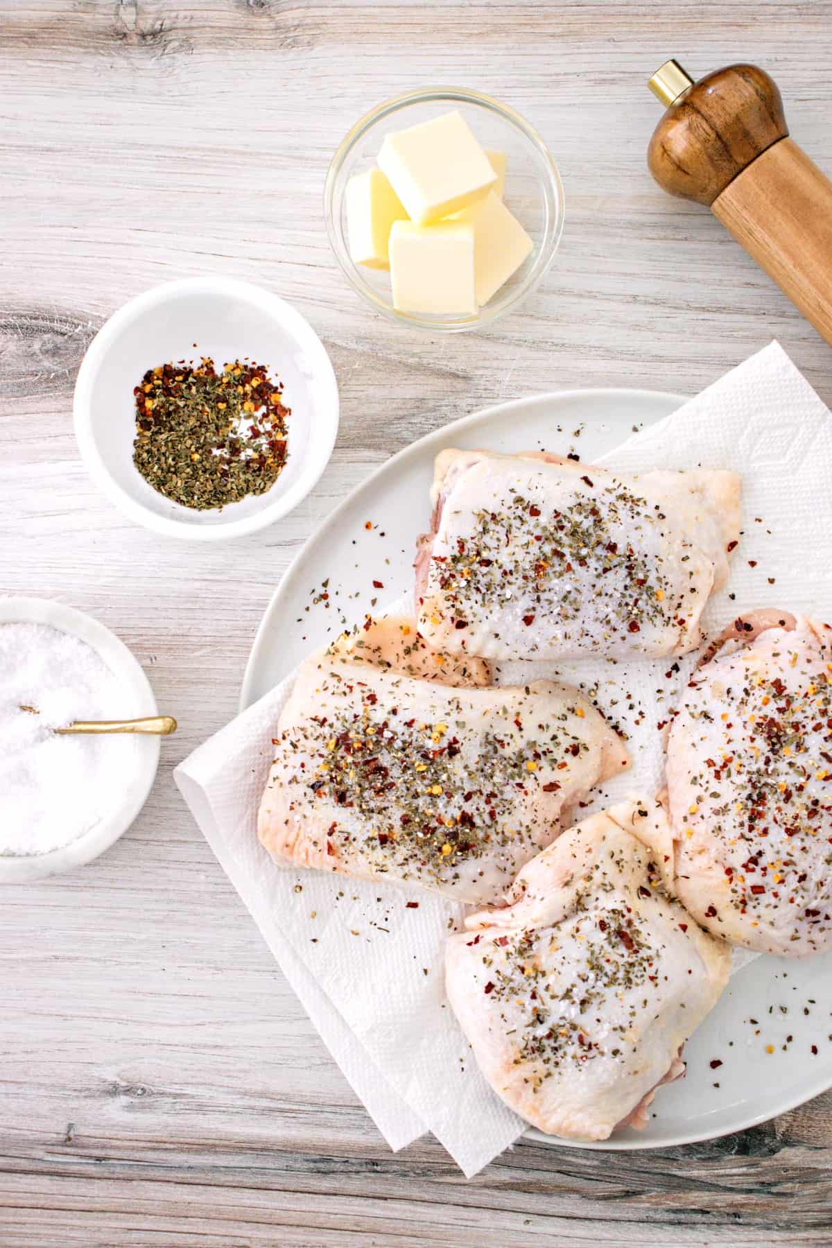 Raw chicken thighs coated generously with seasoning for baked chicken.