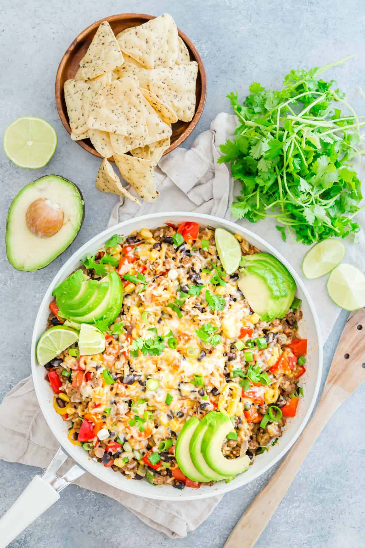 One pan taco skillet served with avocado, tortilla chips, cilantro and cheese.