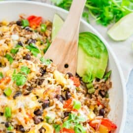 Beef taco skillet garnished with avocado, cheese, and cilantro.