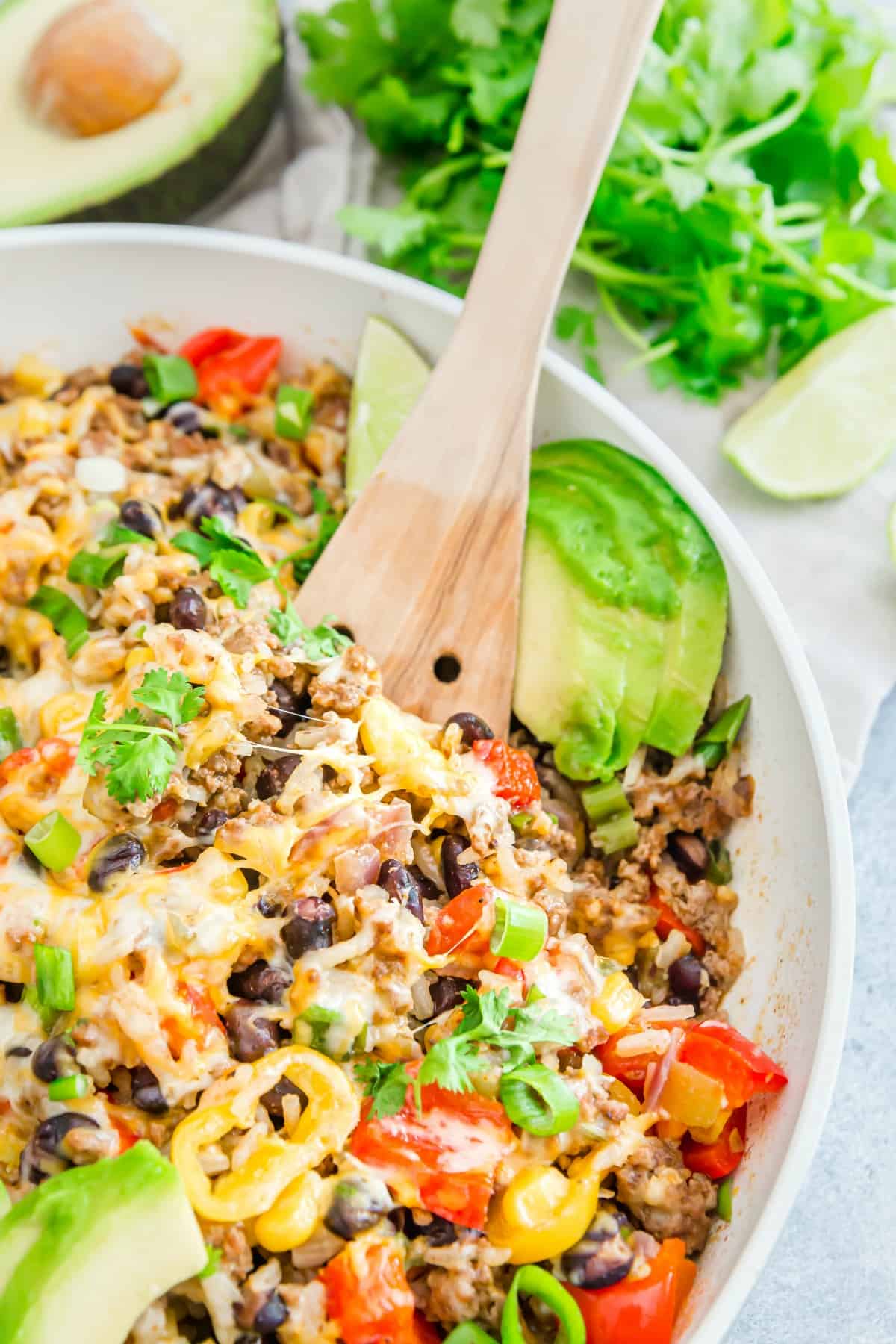 Beef taco skillet garnished with avocado, cheese, and cilantro.