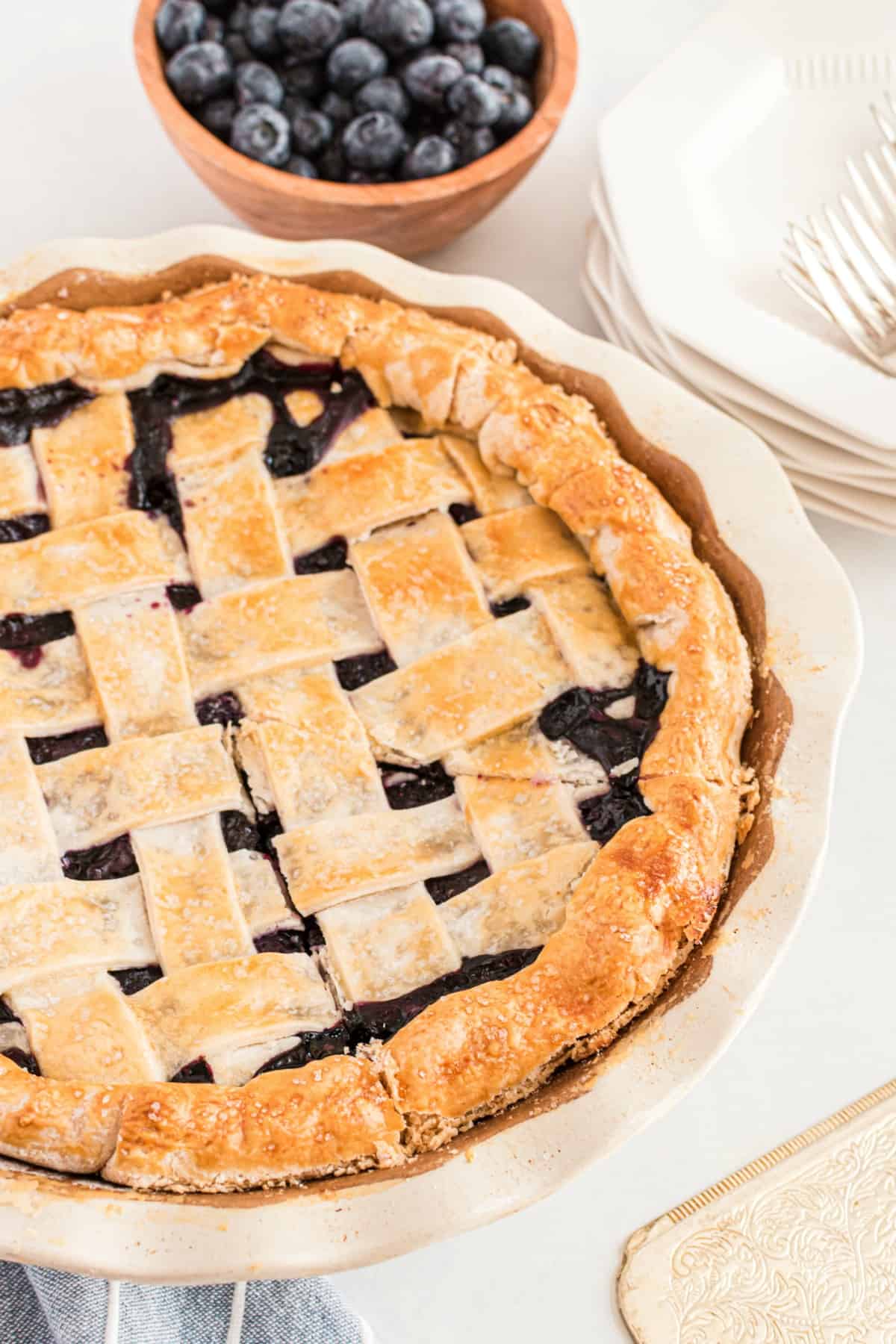 Blueberry pie with lattice crust in a white pie plate.