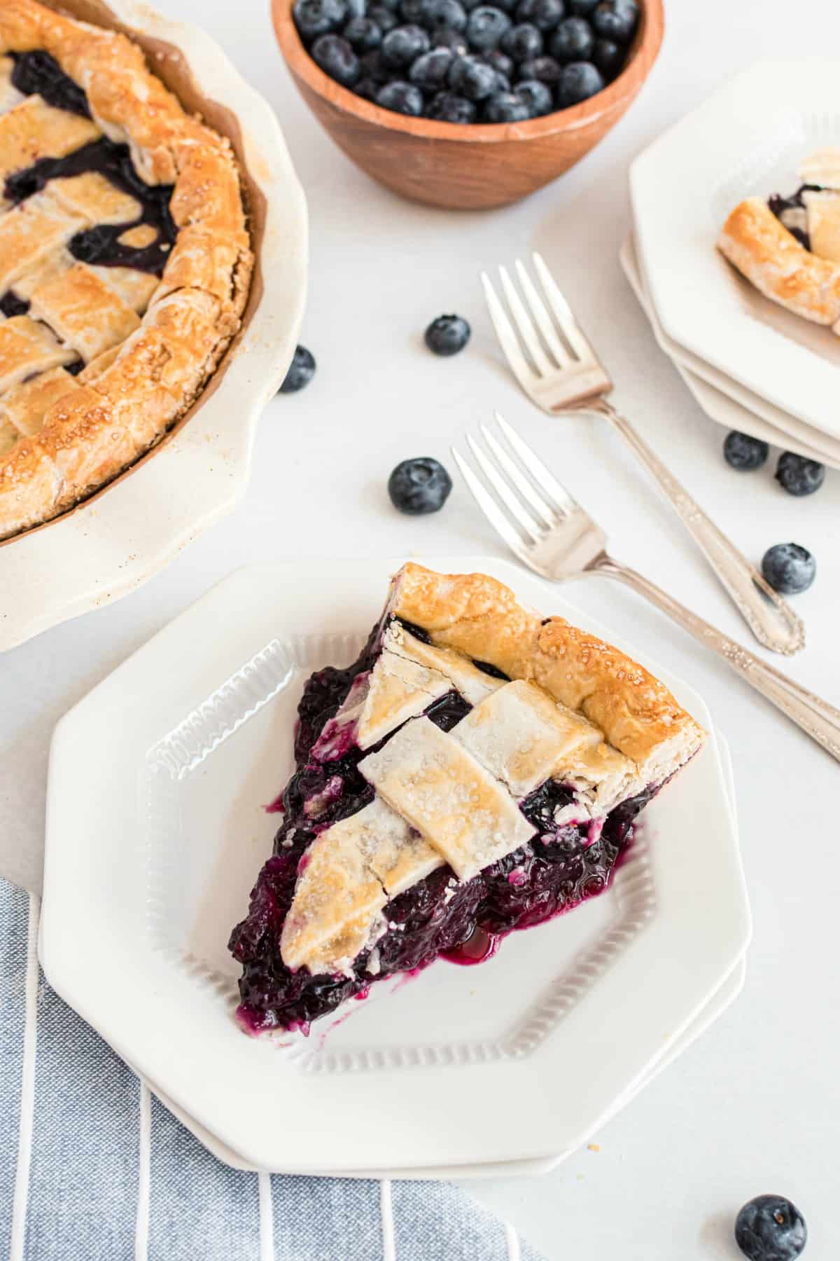 Blueberry pie slice on a white plate.