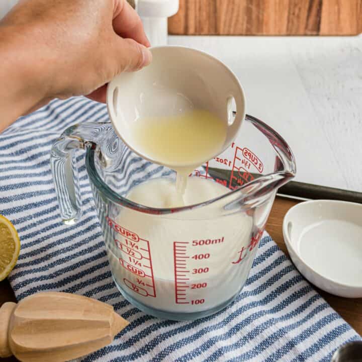 Fresh lemon juice being poured into a glass pyrex with milk to create a buttermilk substitute.