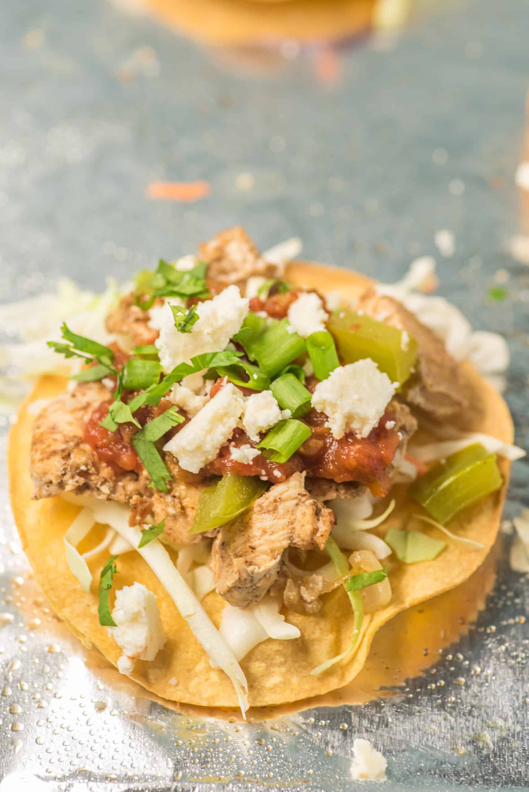 Chicken Tostada with all the fixings on a foil lined baking sheet.