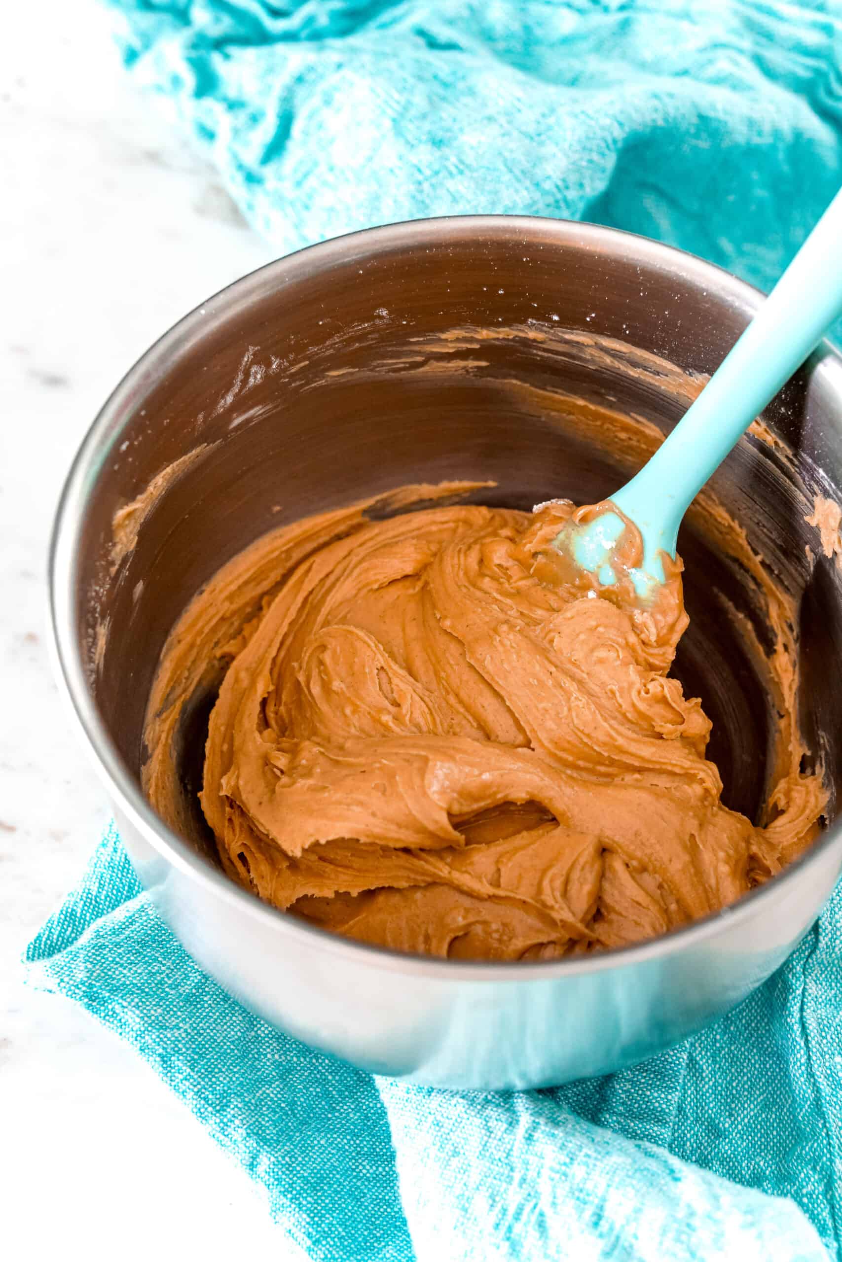 Peanut butter cup filling in a metal mixing bowl with teal napkin beneath the bowl.