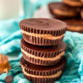 Stack of three homemade reeses peanut butter cups on a teal napkin.