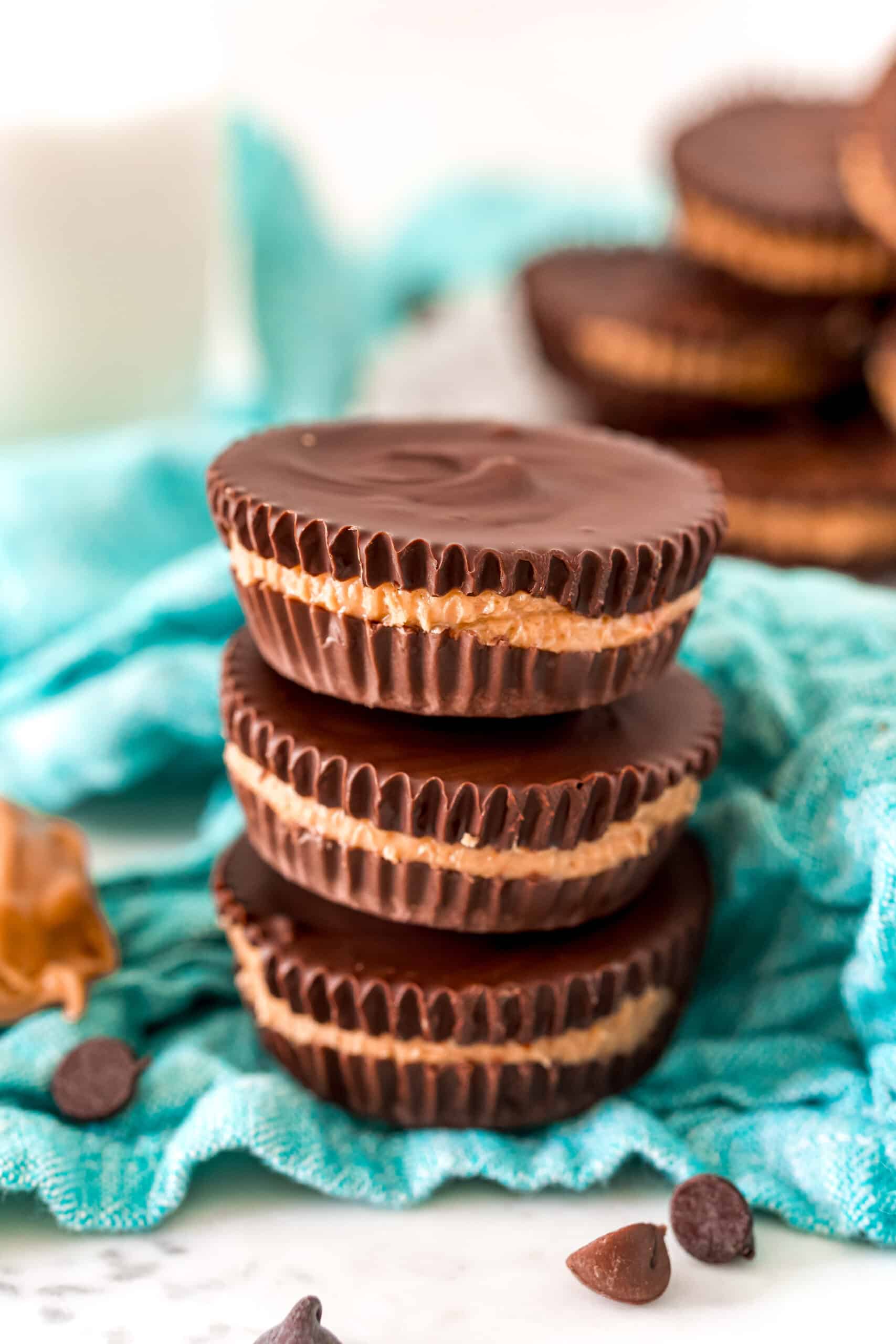 Stack of three homemade reeses peanut butter cups on a teal napkin.