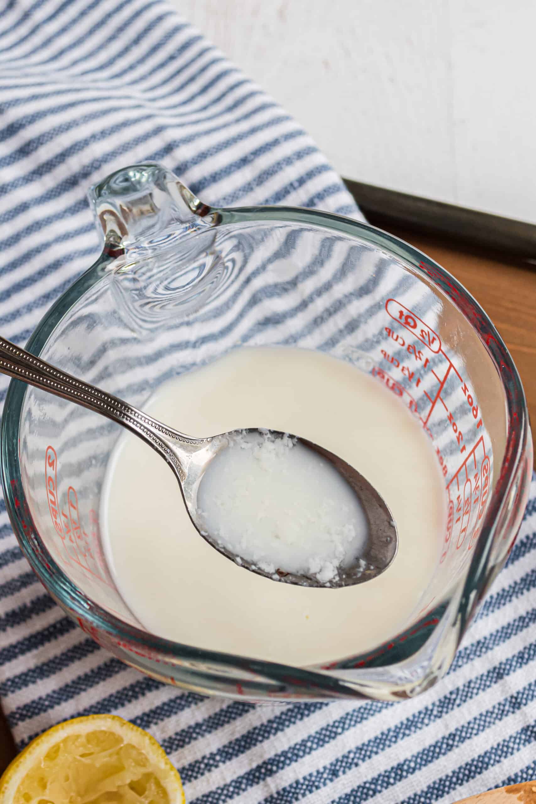 Homemade buttermilk substitute in a glass bowl with a spoon showing it curdled.