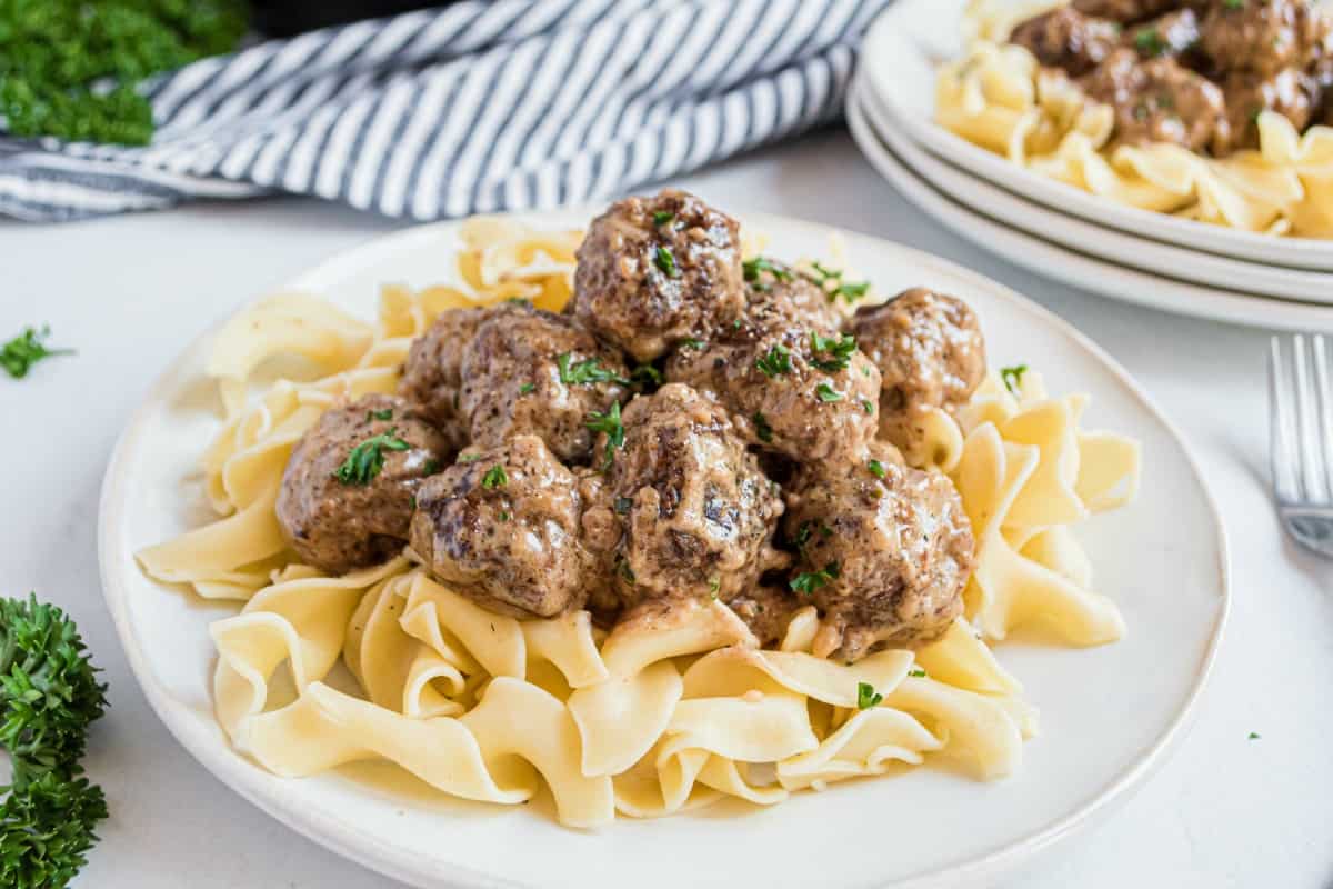 Swedish meatballs with egg noodles on a white plate.