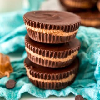 Stack of three peanut butter cups on a teal linen napkin.