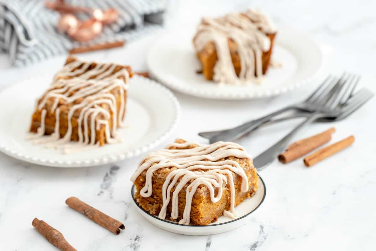 Pumpkin cake with cinnamon cream cheese frosting on three plates.