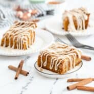 Pumpkin crumb cake with cream cheese frosting, sliced and served on three dessert plates.