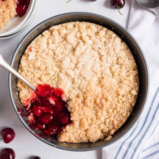 Cherry Cobbler in a springform pan with one scoop missing.