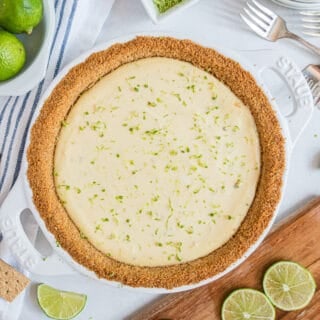 Key lime pie with a graham cracker crust and garnished with lime zest in a white pie plate.