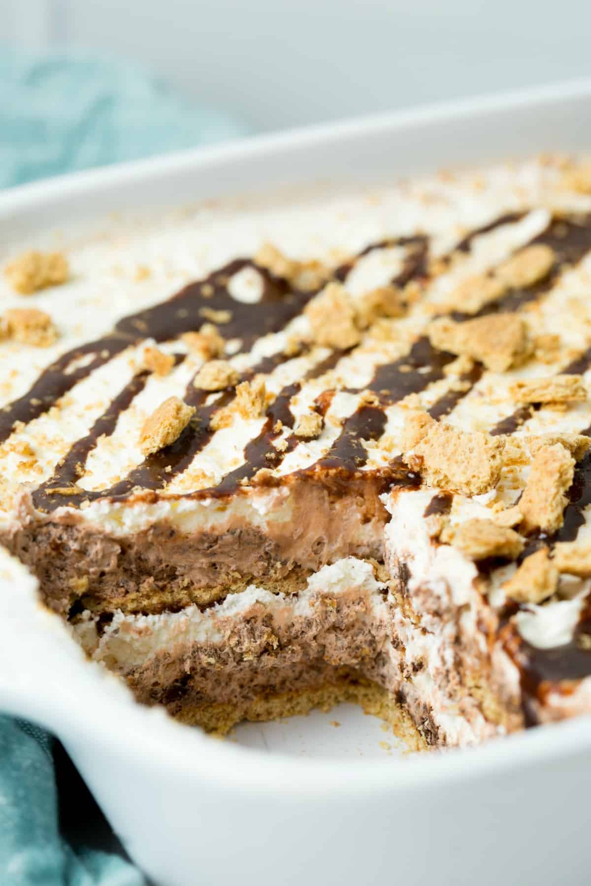 Slice removed from a white baking dish, and the layers of a smores icebox cake can be seen.