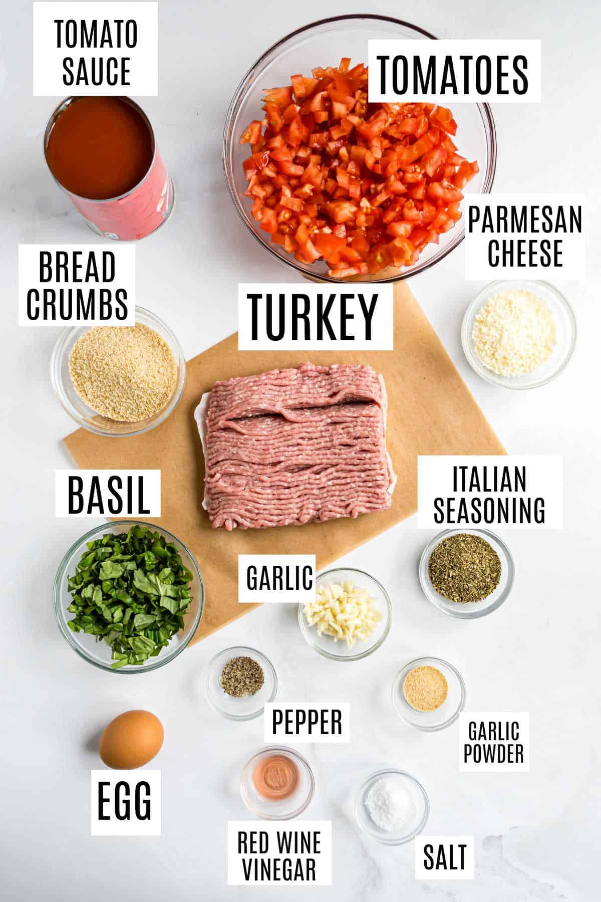 Top-down view of labeled ingredients for turkey meatballs with bruschetta sauce, featuring ground turkey, tomatoes, cheese, and seasonings.
