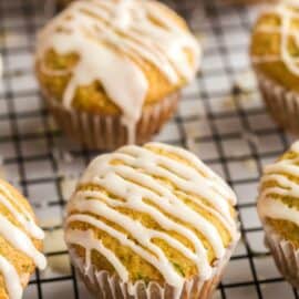 Zucchini muffins on a wire rack drizzled with orange glaze.