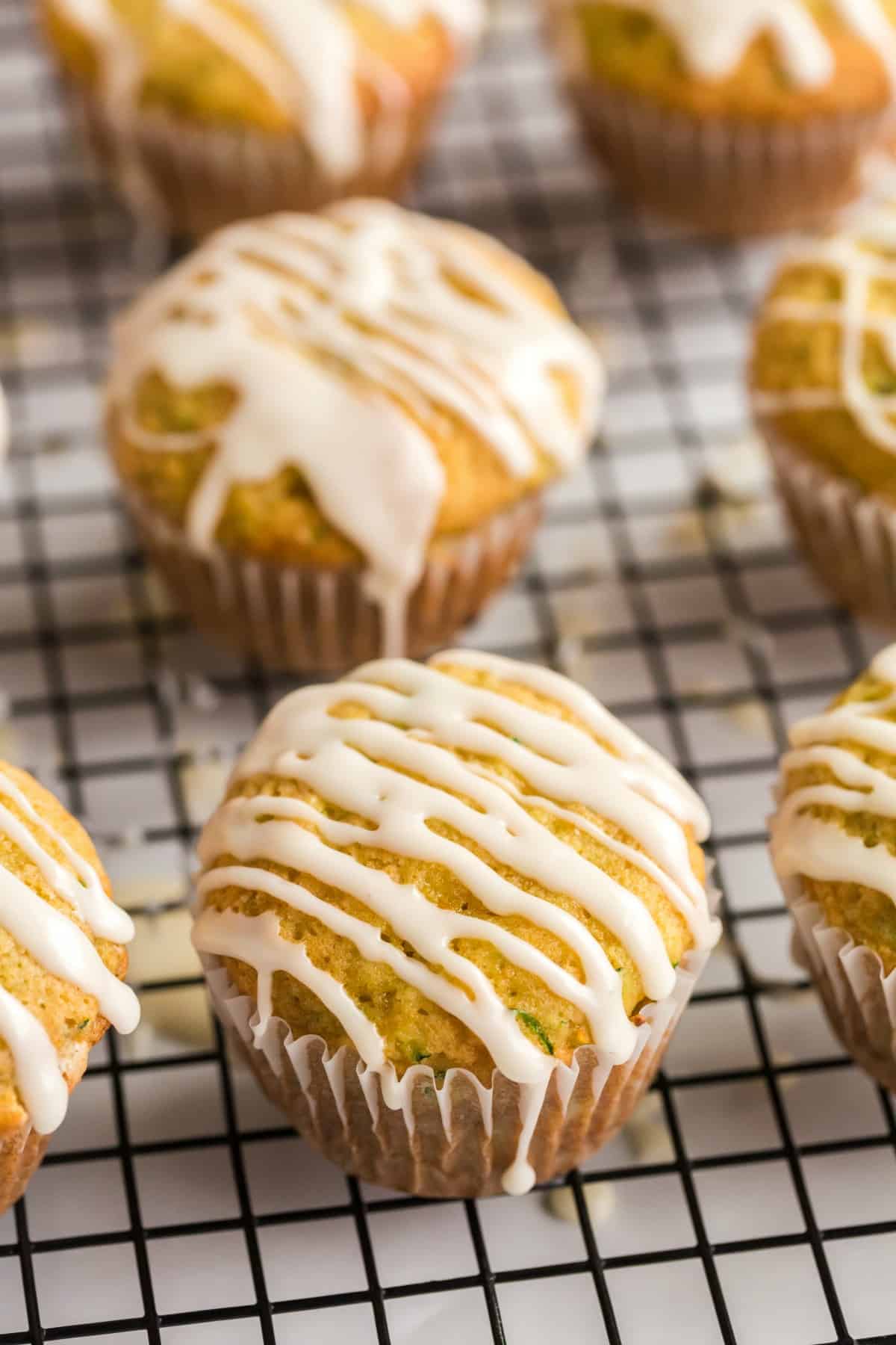 Zucchini muffins on a wire rack drizzled with orange glaze.