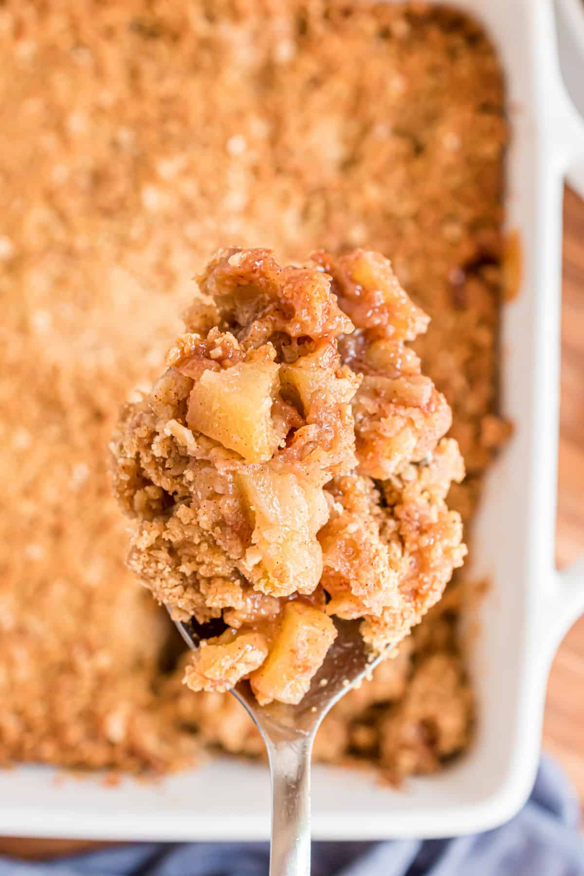 Baked apple crumble being scooped with a large serving spoon.