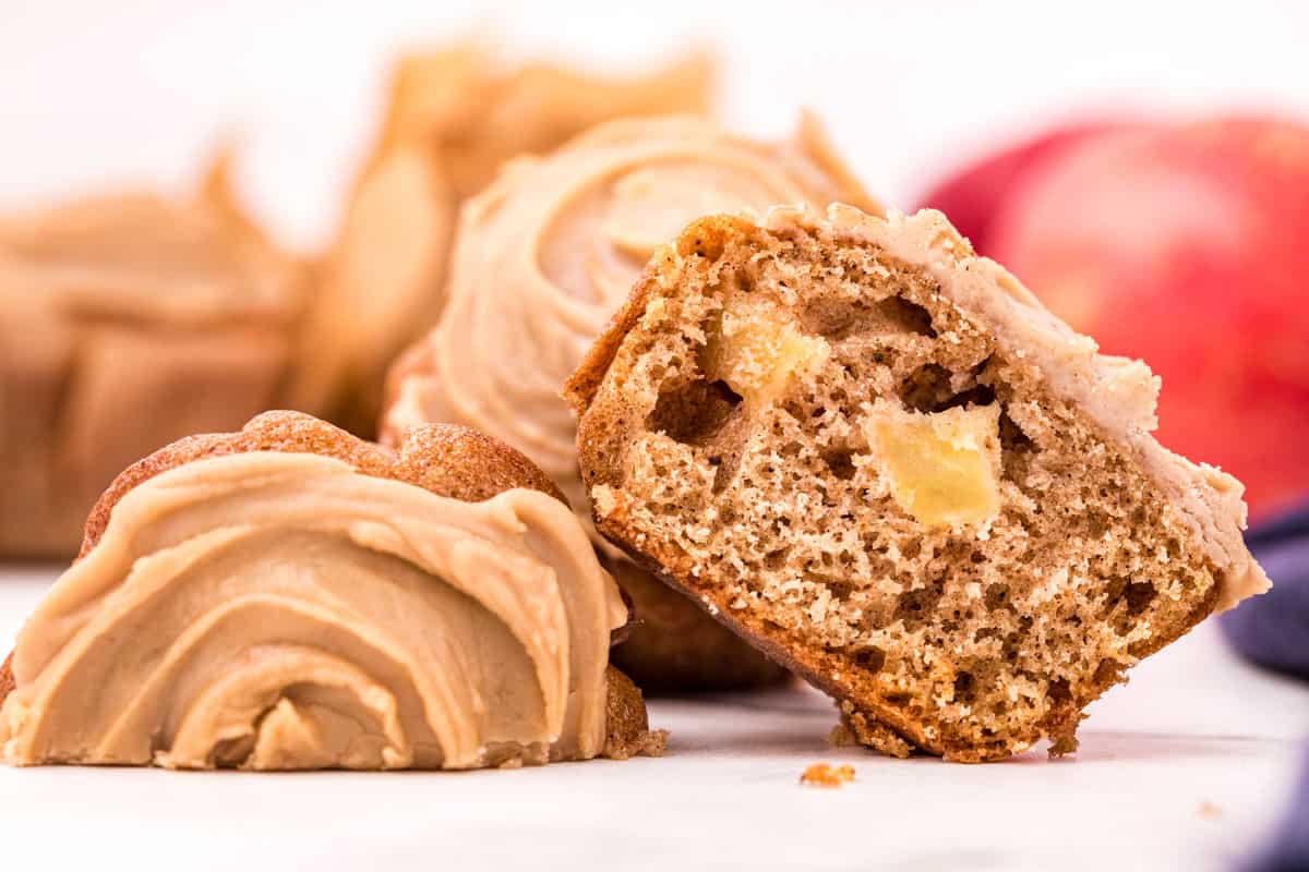 Sliced apple muffins with a swirl of caramel icing on top.