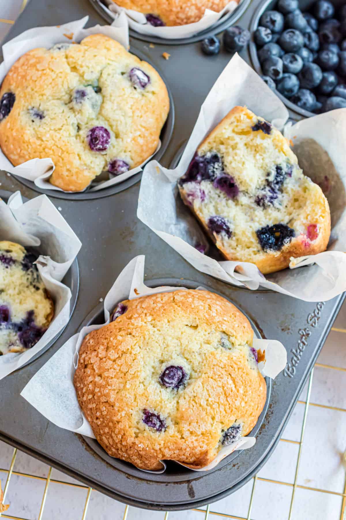 Blueberry muffins in muffin tin, some cut in half.