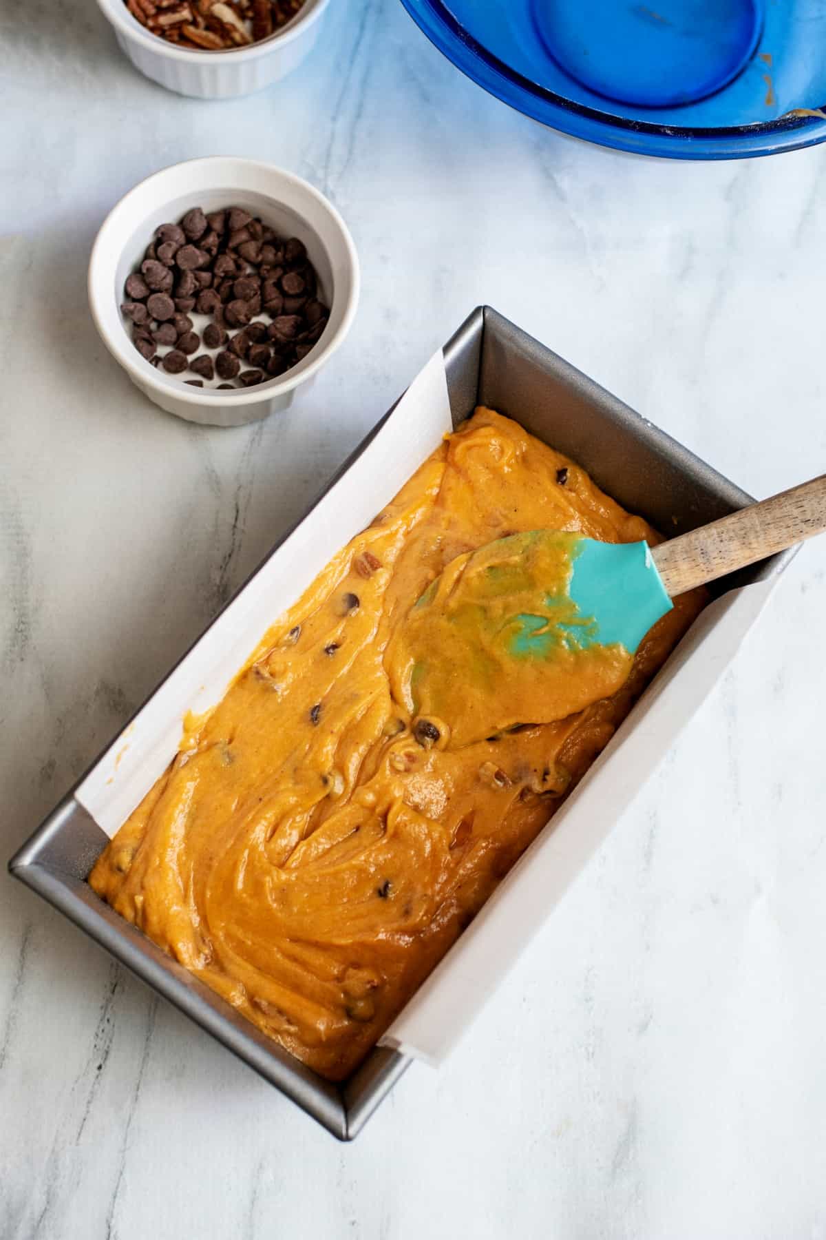 Pumpkin bread batter in a parchment paper lined loaf pan.