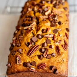Loaf of pumpkin bread topped with chocolate chips and pecans.
