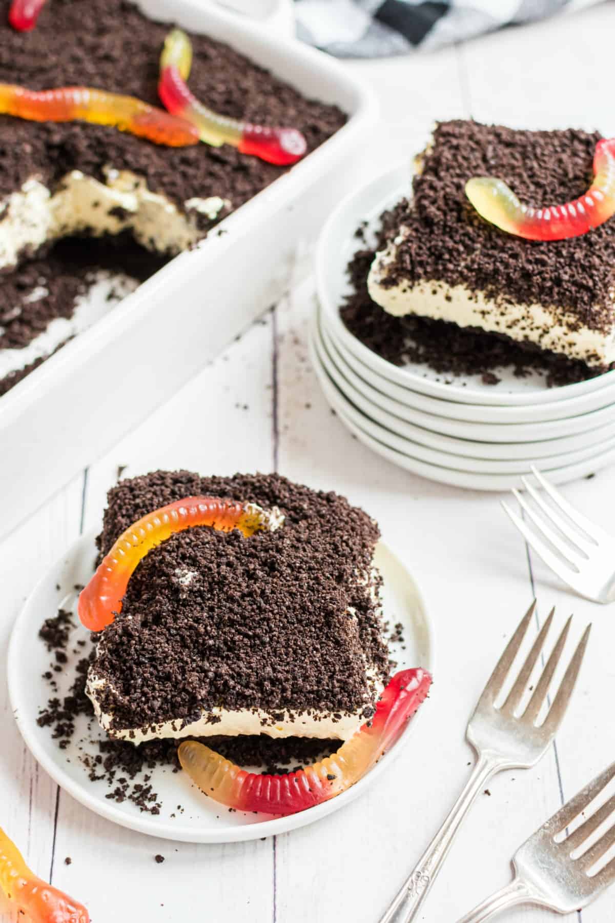 Vanilla dirt cake with gummi worms on top of crushed oreos.